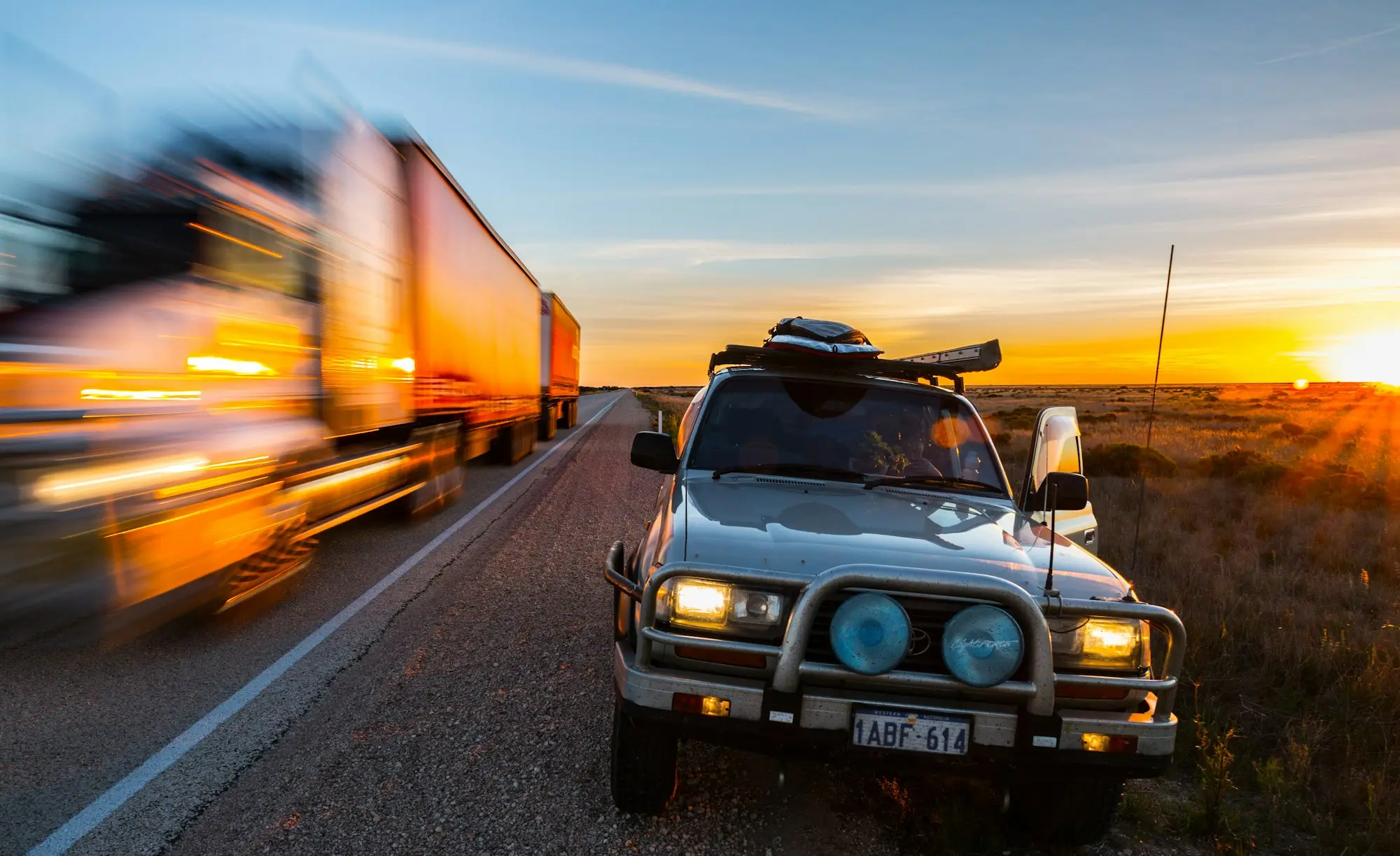 Road train and four-wheel drive on the Nullarbor highway at sunset
